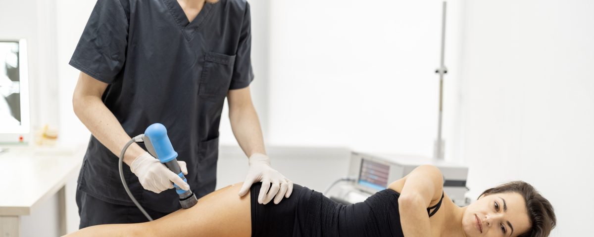 Doctor applies shock wave therapy on women's knee