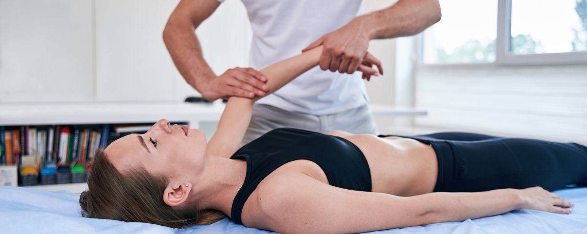 Nice young female getting professional treatment with pain in hand in wellness center