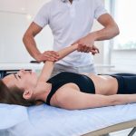 Nice young female getting professional treatment with pain in hand in wellness center