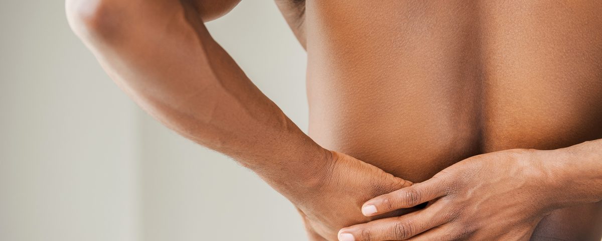 Pain in back. Cropped image of young African man touching his back
