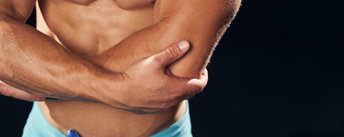 Well-built sportsman feeling muscle pain in his elbow