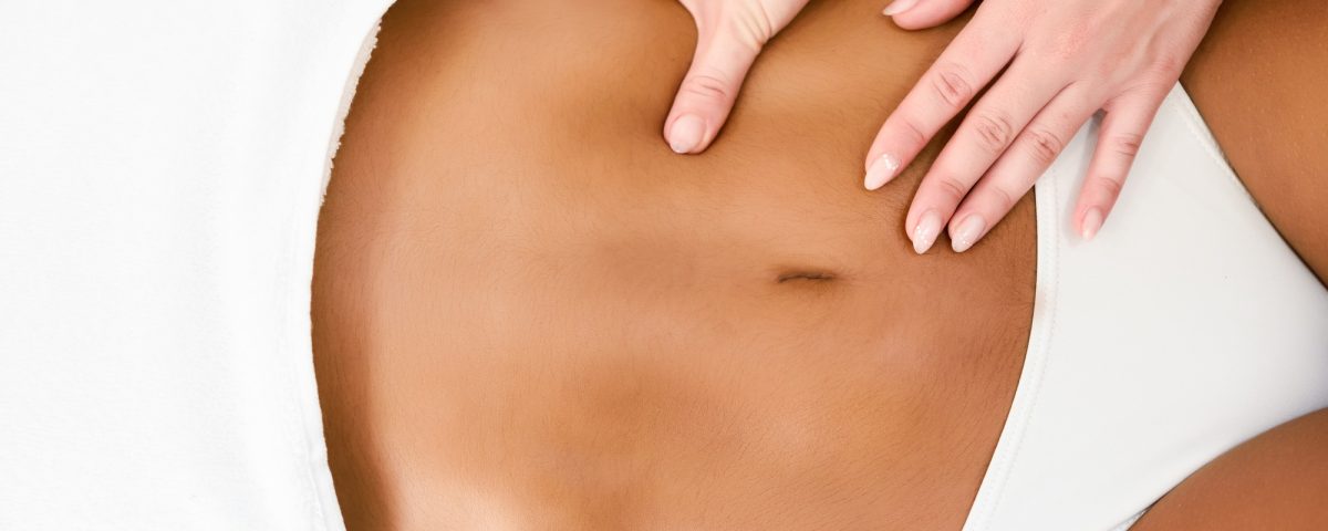 Woman receiving abdomen massage in spa wellness center.
